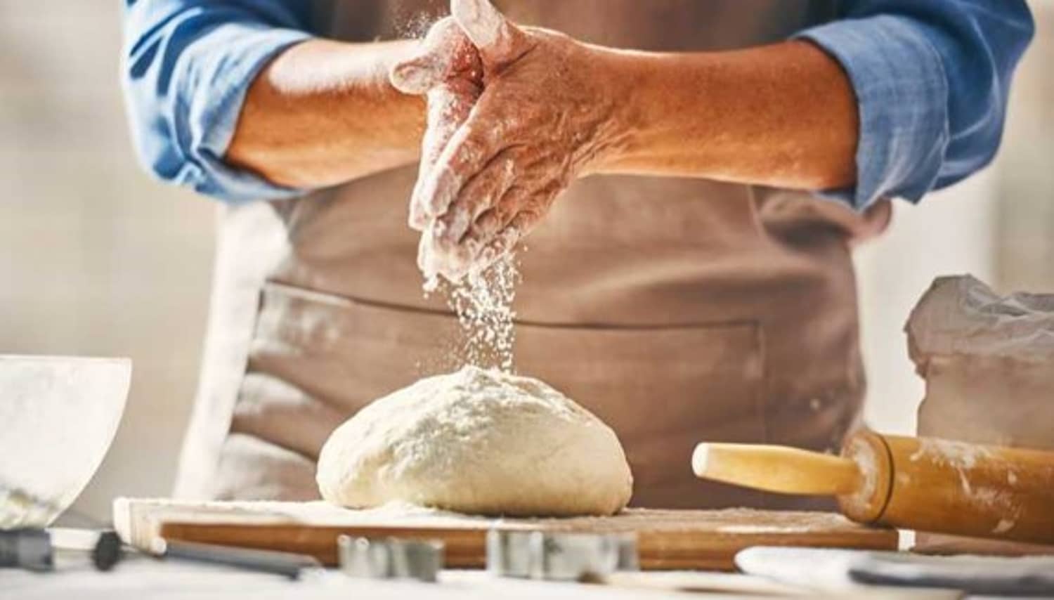 A view of flour falling from hands onto a flour dough ball